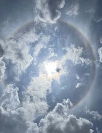 Low angle view of sunlight streaming through clouds