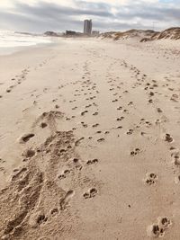 Footprints on sand at beach against sky