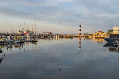  the port of cattolica with the boats and the lighthouse reflecting in the water at sunset