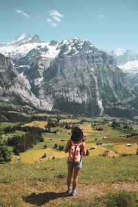 Rear view of man standing on field against mountains