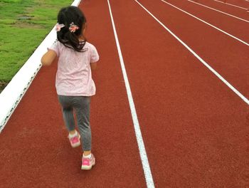 Rear view of girl running on sports track