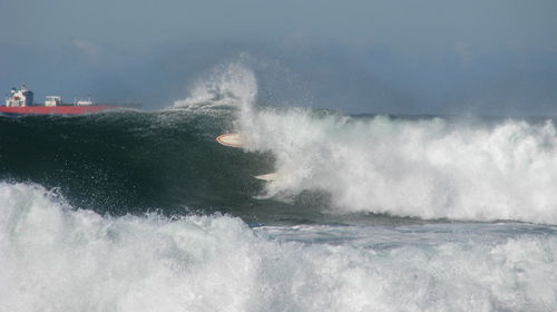Waves splashing in sea against sky