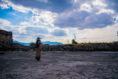 Full length of woman standing against cloudy sky