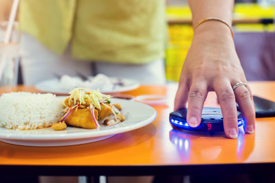 Midsection of man holding ice cream on table