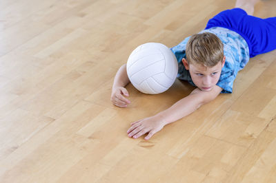 High angle view of boy playing with ball on hardwood floor