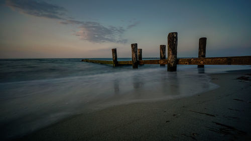 Wooden posts on beach against sky