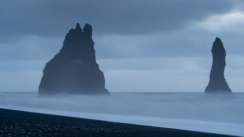 Scenic view of rocks on sea against sky