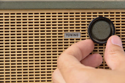 Close-up of hand turning knob on radio