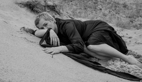 Full length of woman relaxing on sand