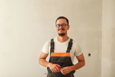 Portrait of young man standing against wall