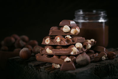 Pile of hazelnut milk chocolate and nuts on dark background