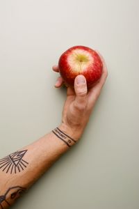 Cropped hand holding apple against white background