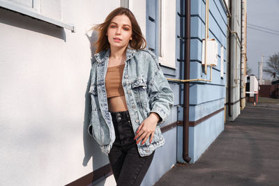 Portrait of young woman standing against building