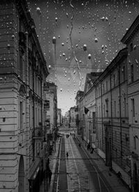 Wet street amidst buildings against sky during rainy season