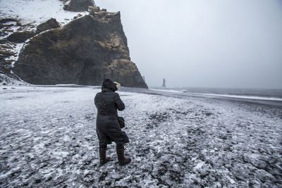 Rear view of man walking on snow covered mountain