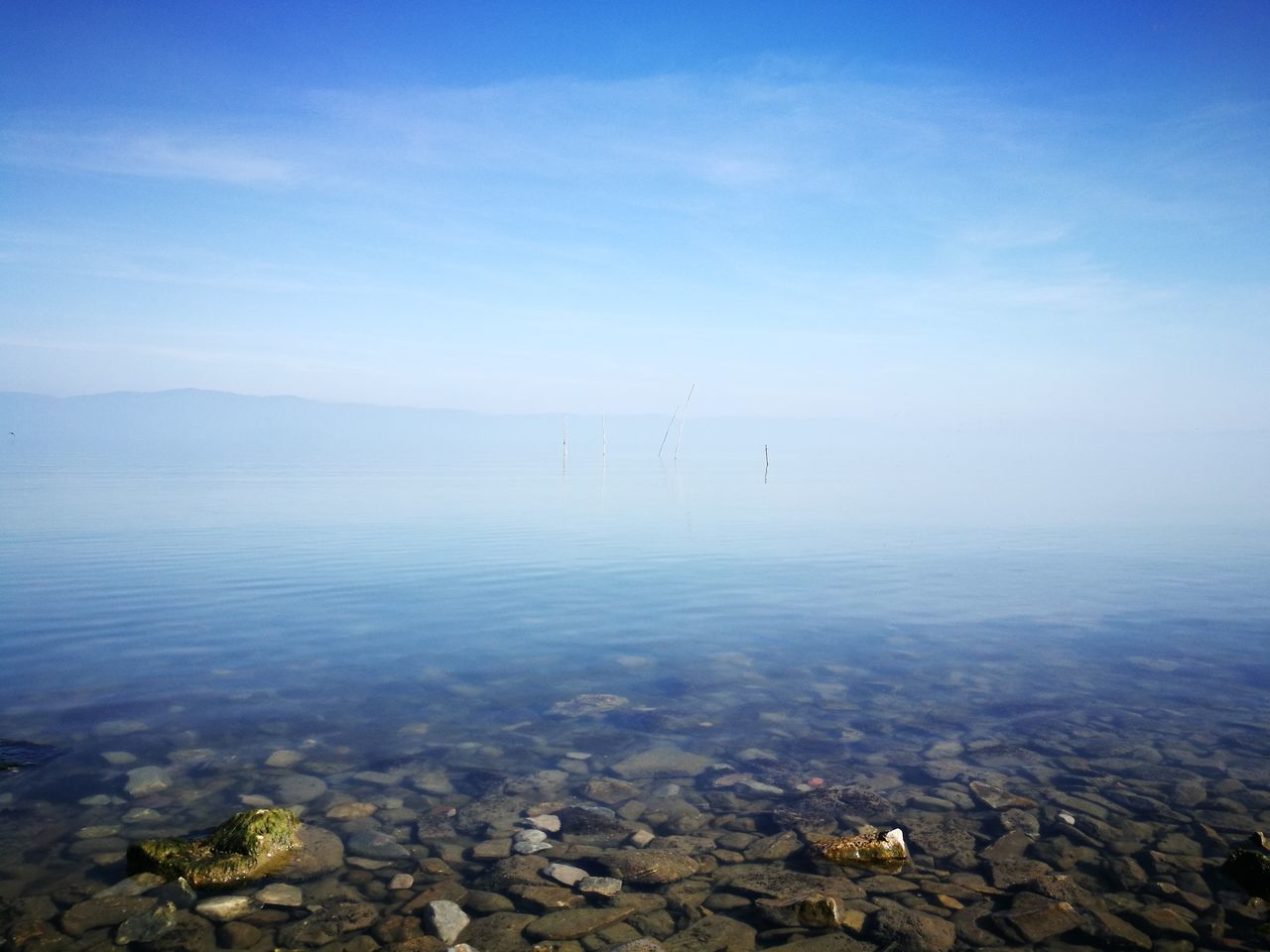 tranquil scene, nature, outdoors, beauty in nature, tranquility, day, sky, wind turbine, wind power, scenics, no people, fuel and power generation, alternative energy, fog, blue, landscape, water, industrial windmill, lake, mountain, windmill