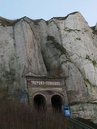 Low angle view of text on cross against sky