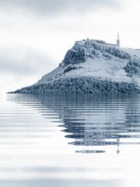 Scenic view of lake by snowcapped mountain against sky