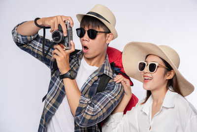 Portrait of happy boy holding sunglasses against white background