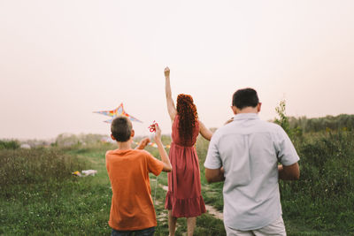 Happy family and children run on meadow with a kite in the summer on the nature.