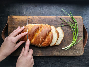 Cropped hand of person cutting bread on board