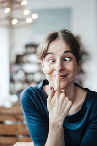 Young woman touching nose while making face in cafe