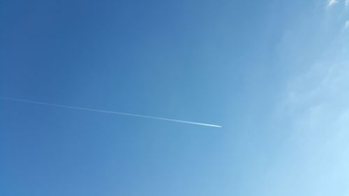 Low angle view of vapor trails in blue sky