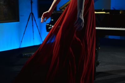 Low section of woman pianist standing in red dress