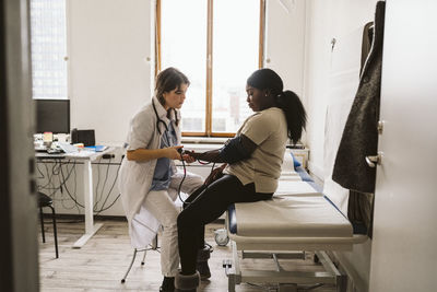 Female healthcare worker measuring young patient's blood pressure in medical clinic