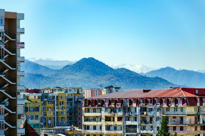 Buildings in city against clear blue sky