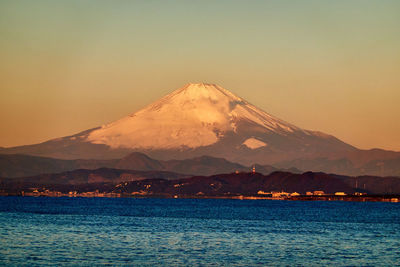 Scenic view of sea against mountain during sunrise