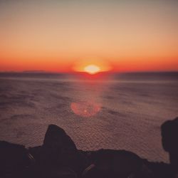 Low section of person on beach against orange sky