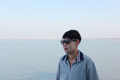 Portrait of woman wearing sunglasses standing against sea