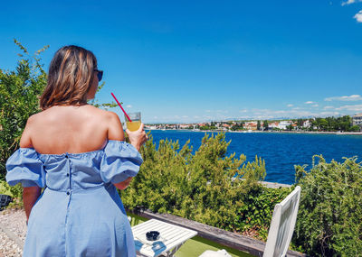 Rear view of young woman in bar by sea. summer, vacation, zadar, croatia.