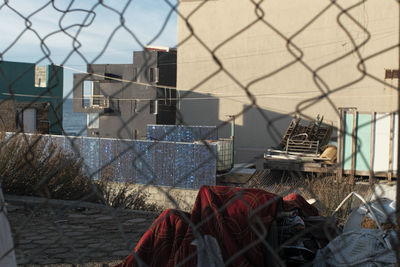 Abandoned building by fence against sky