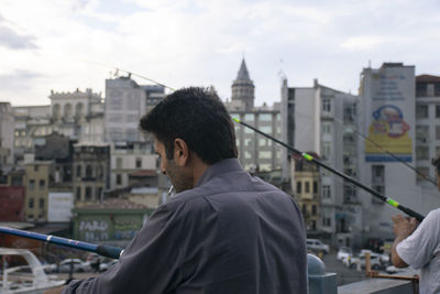 Rear view of man standing against buildings in city