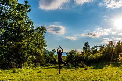 Man on field by trees against sky