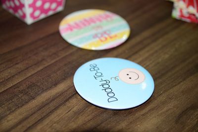 Close-up of daddy to be text on badge at wooden table