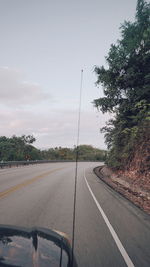 Road by trees against sky