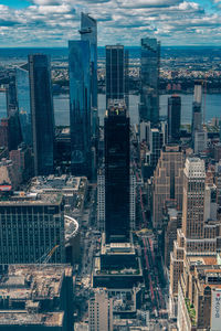 Aerial view of illuminated skyscraper buildings in city at day at high angle