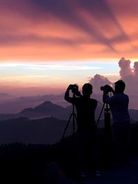 Silhouette people photographing against sky during sunset