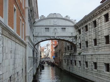 Arch bridge over canal amidst buildings in city