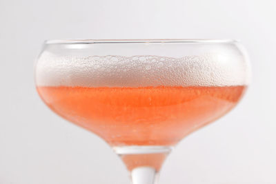 Close-up of orange drink in glass against white background