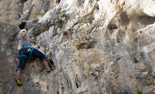 Low angle view of man climbing on rock