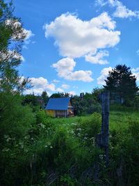 House on field by trees against sky