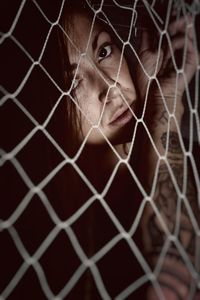 Portrait of young woman seen through netting