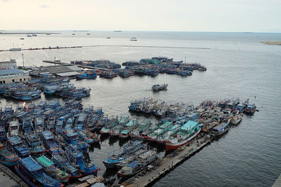 High angle view of boats moored at harbor against sky