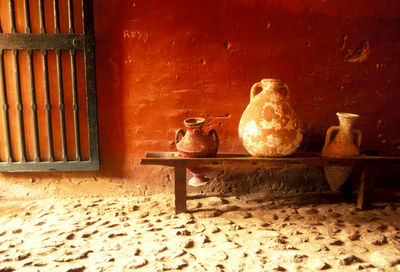 Old earthenware on wooden structure against wall