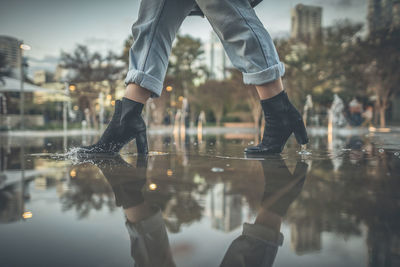 Low section of woman walking in puddle