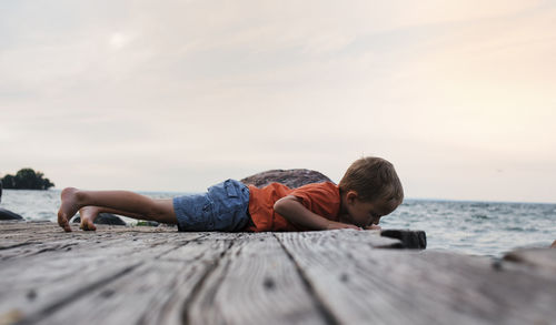 Full length of boy lying on pier against sky